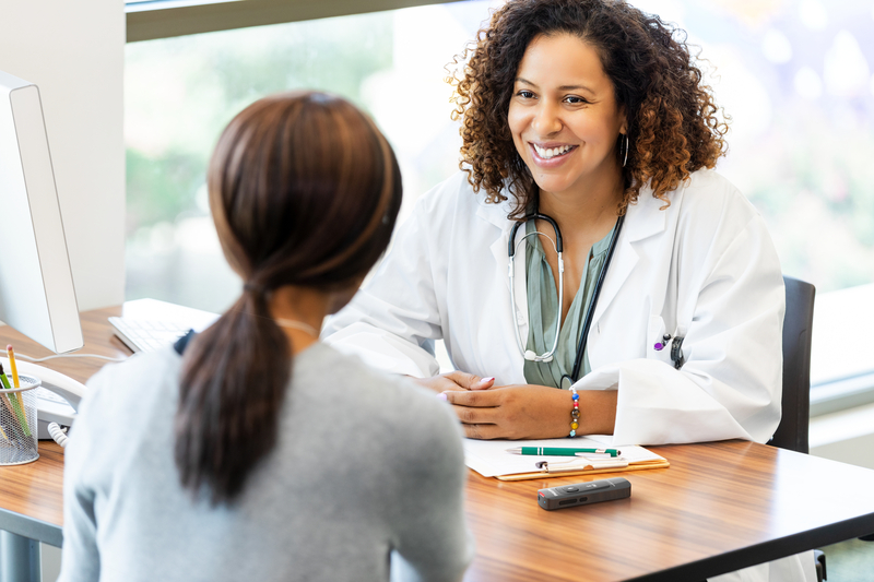 Médecin souriante en consultation avec une patiente, illustrant la confiance et la protection des données médicales.